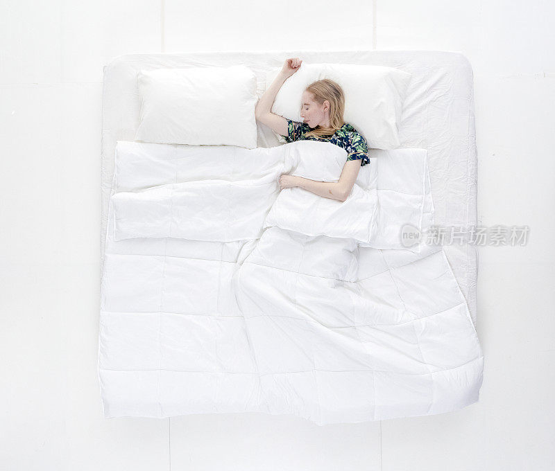 上图/全身/一个20-29岁的成年美丽白人女性/年轻女性躺下/午睡/睡觉/放松/休息在卧室的白色背景穿着睡衣/性感/诱惑